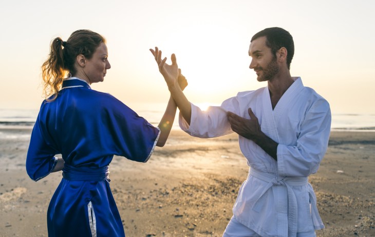 Couple training martial arts on the beach